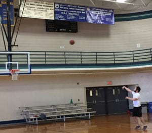 A member of the J shoots a three-pointer in the gym beneath the banners to past Drew Corson Regional Basketball Tournament champions.